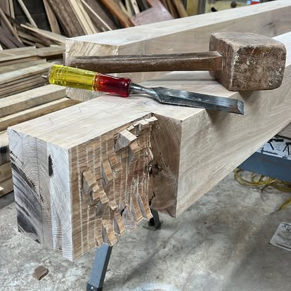 Traditional mallet and chisel beside hand-cut timber joinery